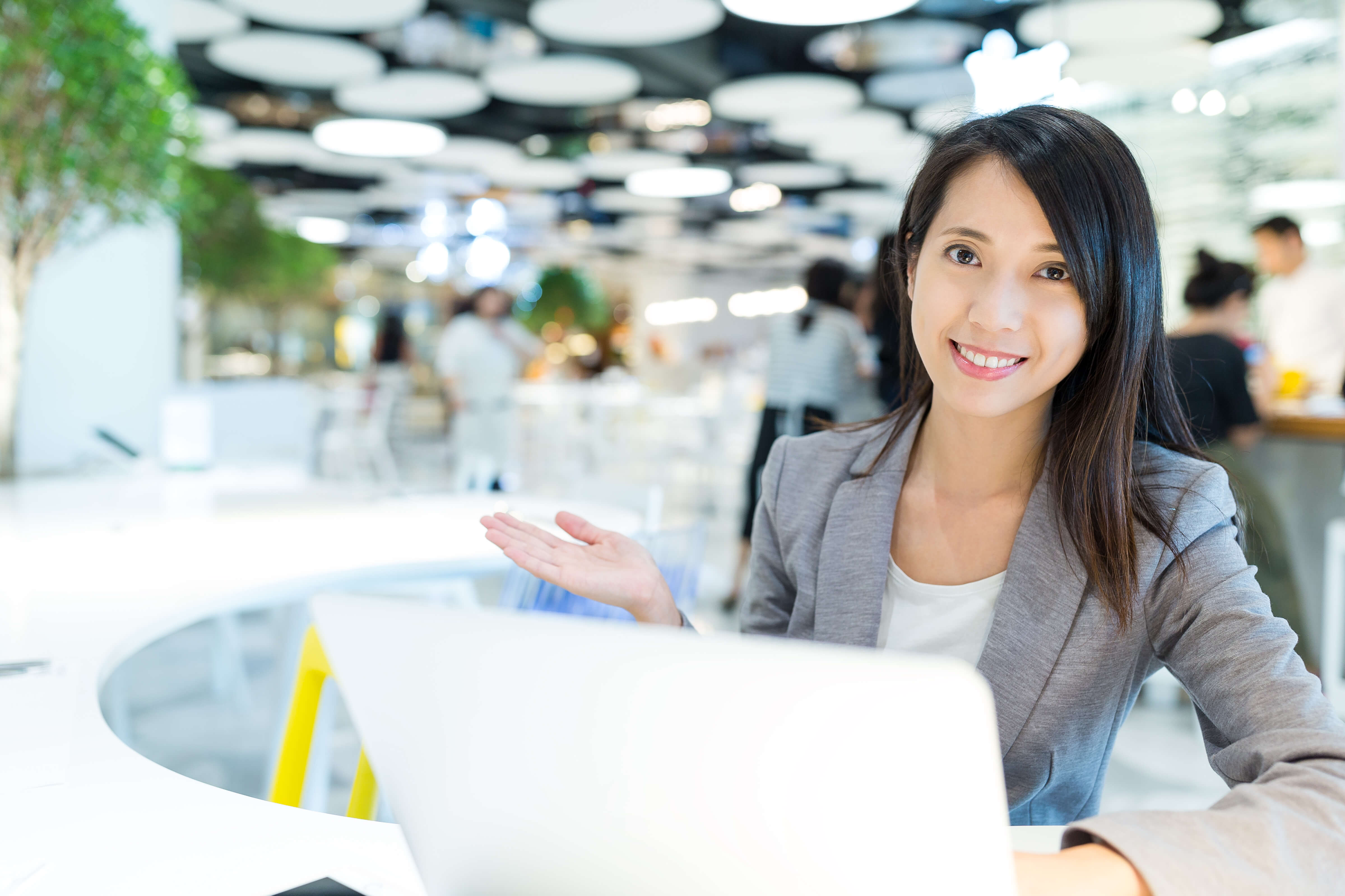 Femme souriante assis devant son portable dans un bureau de coworking
