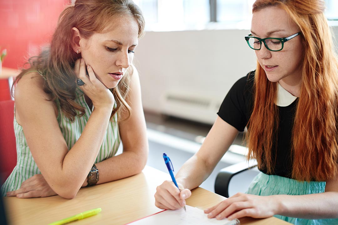 Two coworkers discussing a project at a office table