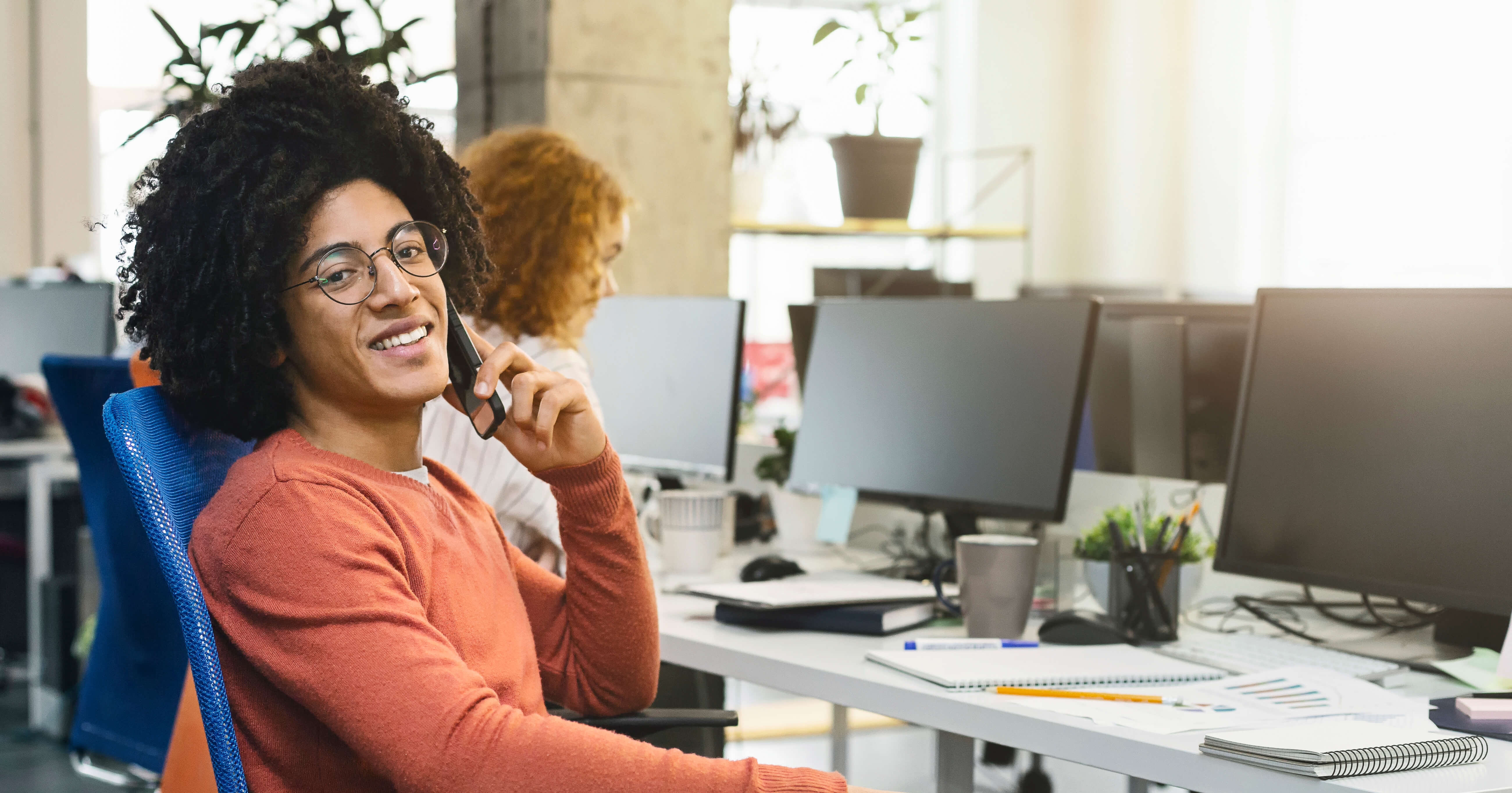 homme ayant une conversation avec son smartphone devant son bureau de coworking